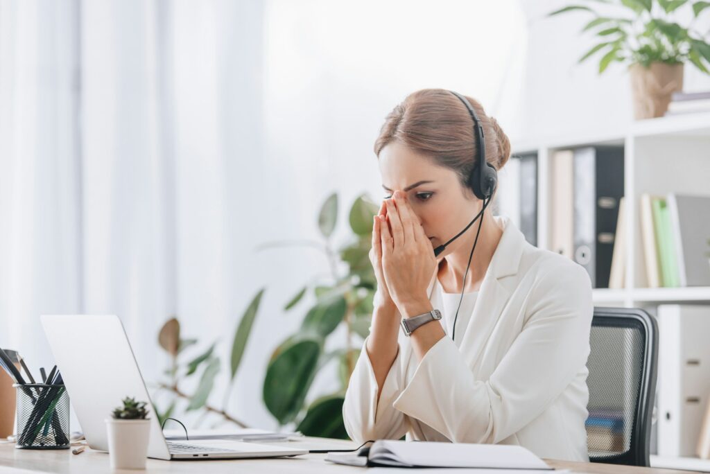 scared female operator working with headset and laptop in call center