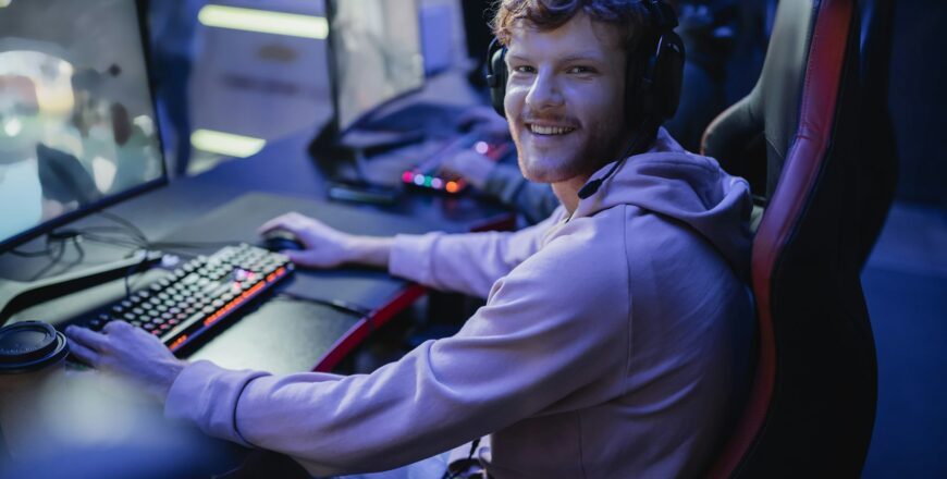 Smiling gamer looking at camera while playing video game in cyber club