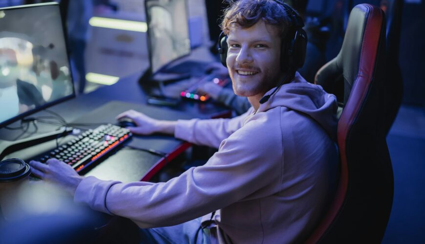 Smiling gamer looking at camera while playing video game in cyber club