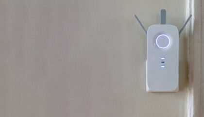 Wifi Extender on grey empty wall background. Wireless repeater, network booster. Copy space.