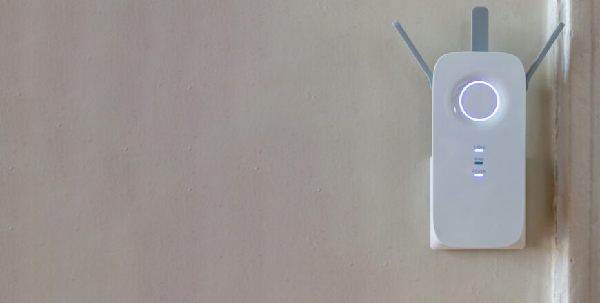 Wifi Extender on grey empty wall background. Wireless repeater, network booster. Copy space.